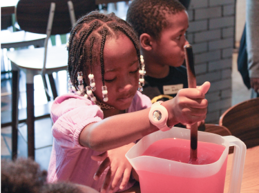 girl mixing lemonade in pitcher